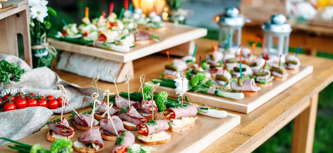 Beautiful catering banquet buffet table decorated in rustic style in the garden. Different snacks, sandwiches. Outdoor.